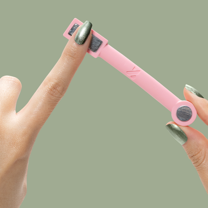 Fingers with Jade Velvet nail polish using a pink magnetic tool to create shimmer effects on matte green nails