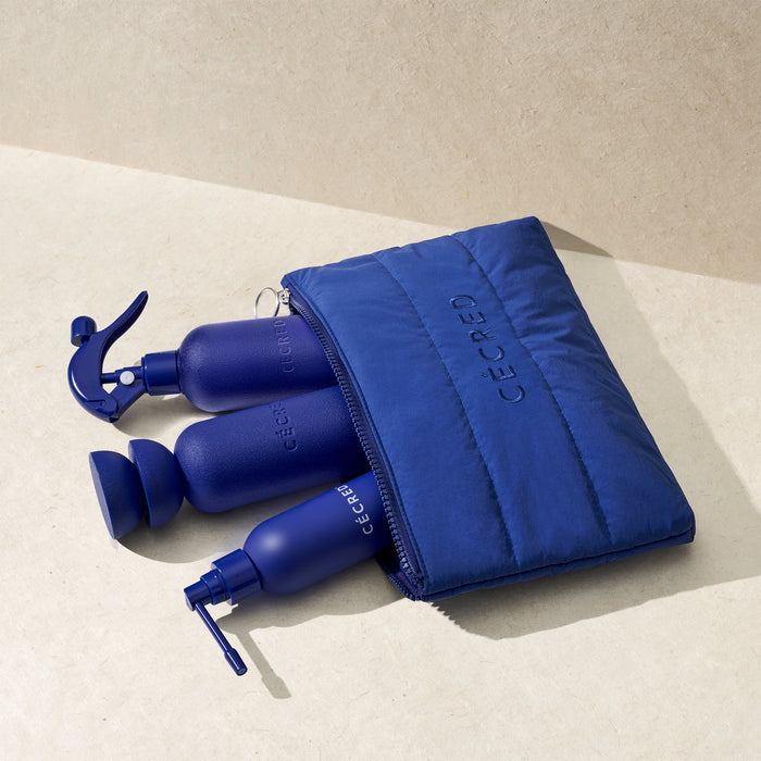Blue travel bottles with a matching pouch on a beige surface