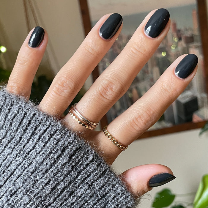 Hand with glossy deep charcoal gray nails polished in Last Minute Shopping gel polish for at-home manicure