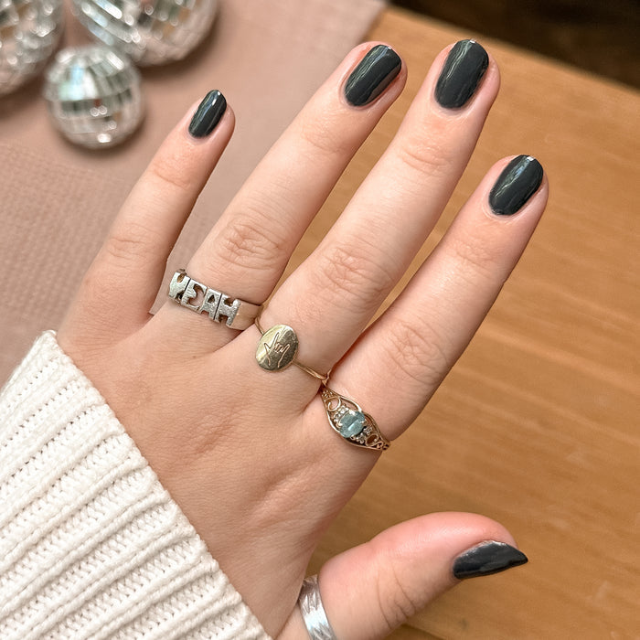 Hand with neatly polished nails in deep charcoal gray Last Minute Shopping gel polish by Olive and June for at-home mani