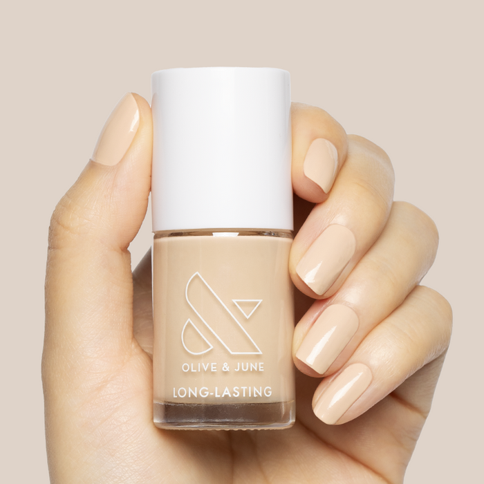 Hand holding Line Dancing Boots polish with nails painted a neutral toasted cream shade for an elegant manicure look