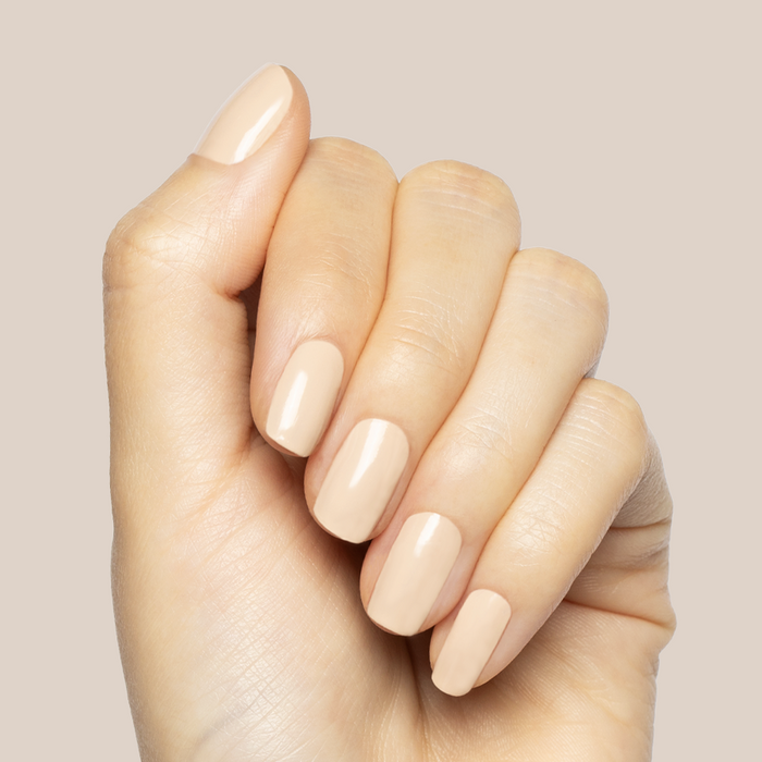 Hand with medium-length nails painted creamy neutral shade using Line Dancing Boots polish for a polished mani