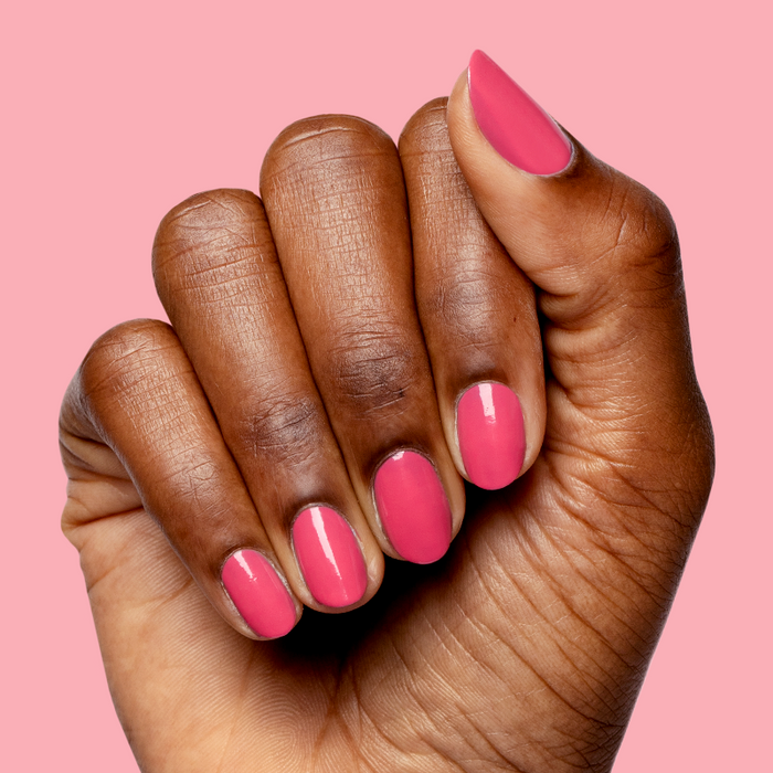 Hand with nails painted in bright hot pink Love All polish for a glossy and vibrant at-home manicure look