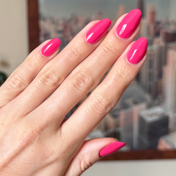 Hand with glossy nails painted in bright hot pink Love All for a vivid and long-lasting at-home manicure look