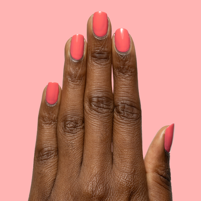 Hand with smooth gel polish nails painted in Maine Character Energy for a bright, lobster red manicure look