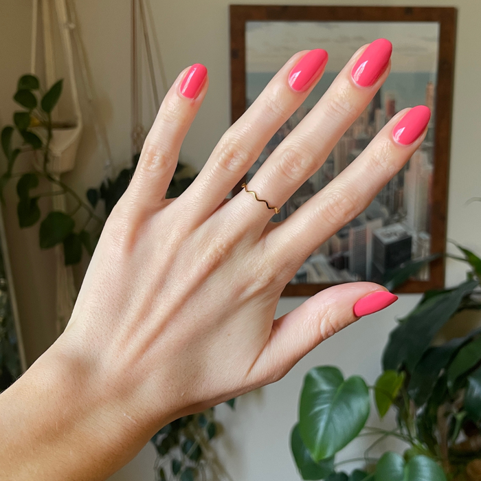 Hand with glossy nails painted in Maine Character Energy showing a vibrant lobster red gel polish manicure