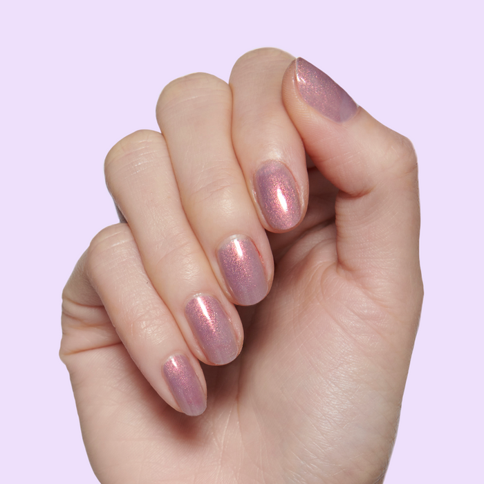 Fingernails painted with Mermaid Hair iridescent polish showing pink, purple, and gold shimmer on neutral background