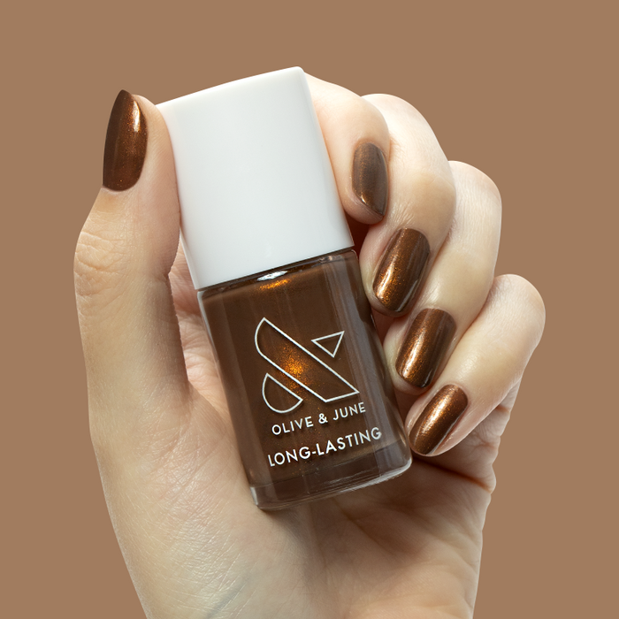 Hand holding Olive and June Milk Chocolate gel polish with milky brown iridescent manicure on medium nails