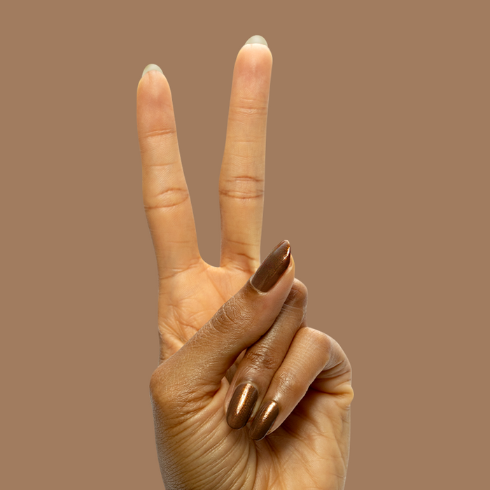 Hand displaying peace sign with long nails painted in Milk Chocolate gel polish on brown background