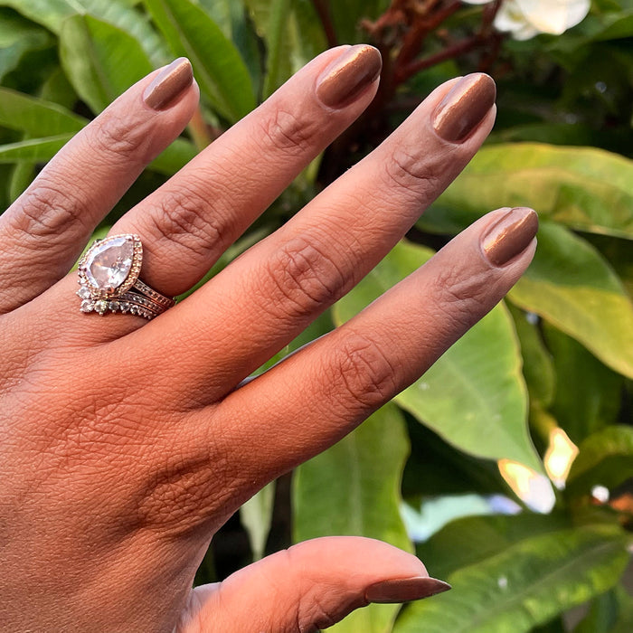 Hand with medium-length nails painted in Milk Chocolate gel polish showing warm brown tone with golden iridescence outdoors