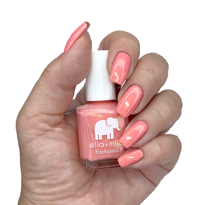 Mystical coral shimmer nail polish on a medium skin tone, hand holding the bottle