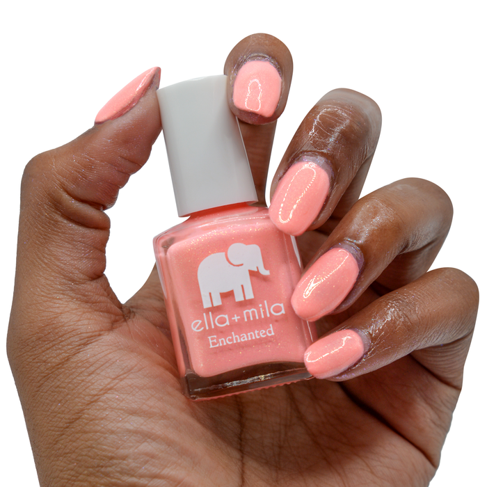 Mystical coral gold shimmer nail polish on a deep skin tone, hand holding the bottle