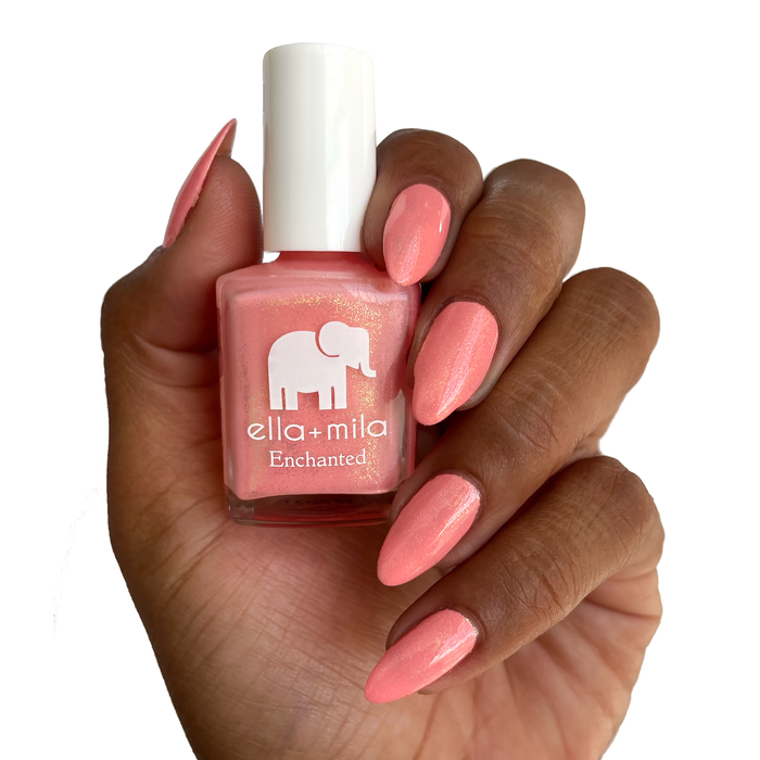 Mystical coral gold shimmer nail polish on a deep skin tone, holding the bottle
