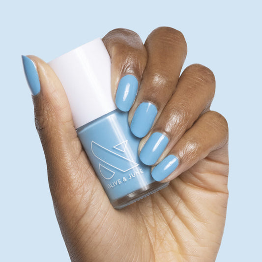 Hand with nails painted in cloudless sky blue using Not a Cloud polish holding matching bottle