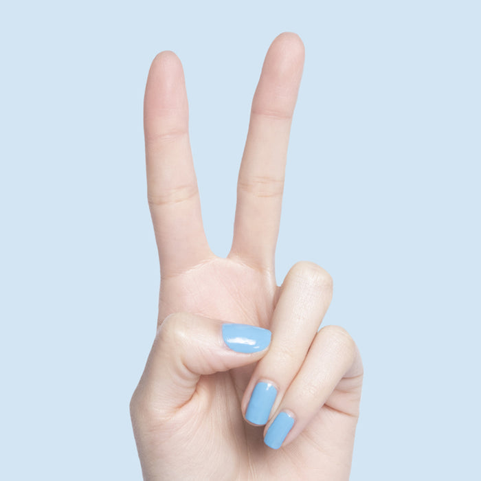 Hand showing nails painted with Not a Cloud blue gel polish for a fresh quick dry manicure by Olive and June