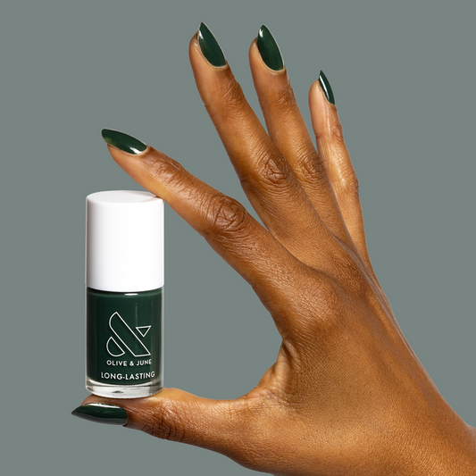 Hand with dark emerald green nails holding One For You, Two For Me gel polish bottle by Olive and June