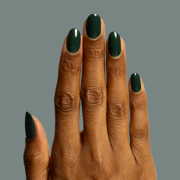 Hand with glossy moody dark emerald green nails polished in One For You, Two For Me gel polish for at-home mani