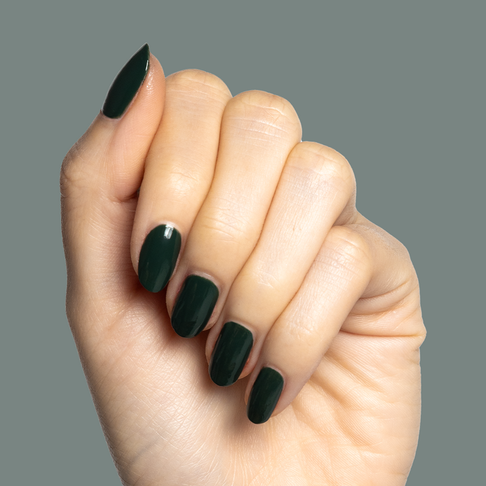 Hand showing neatly shaped nails painted in One For You, Two For Me dark emerald green gel polish manicure
