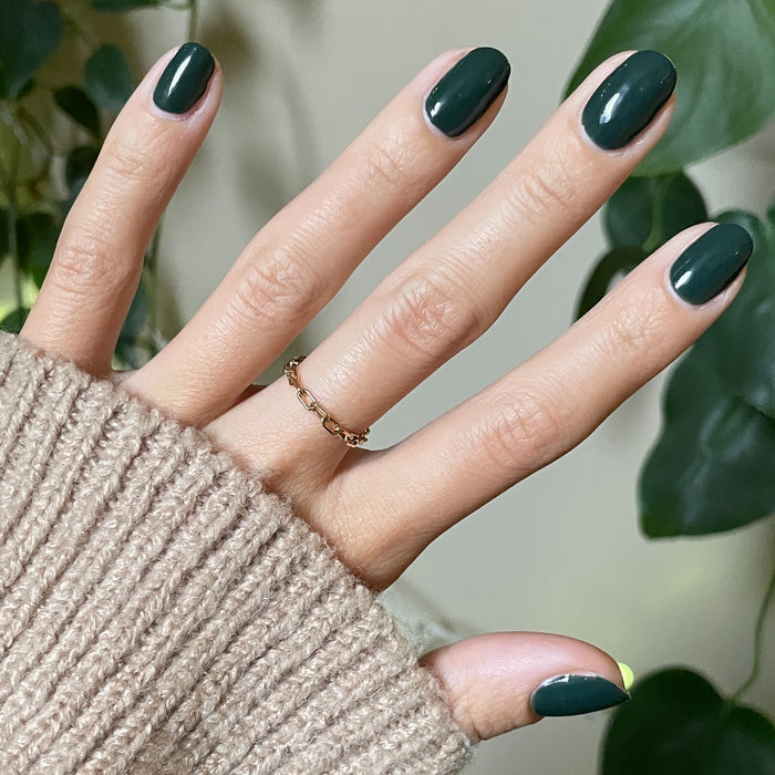 Hand with smooth nails painted in One For You, Two For Me gel polish showing dark emerald green mani