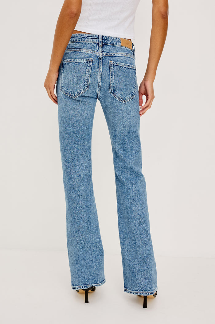 Fremont Petite Low Rise Bootcut Jean in Light Stretch Denim With Extended Inseam, 5-Pockets, Distressed Details, Belt Loops, and Zip-Fly Closure in Old Indigo Colorway - Lower Body Back View Featured on Model
