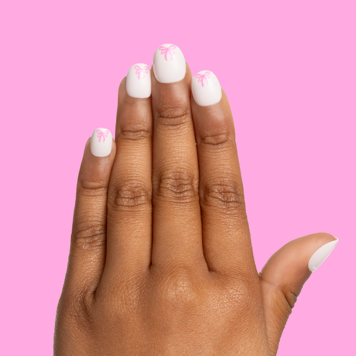 Pink Everything Please - Pressies | Extra Short Short | Round showing white press-on nails with pink ribbon design on hand against pink background