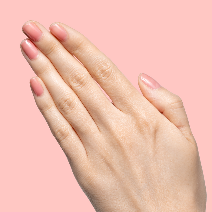 Hand with sheer warm peach pink glossy nails showcasing Pink Pineapple Gloss for a subtle at home manicure