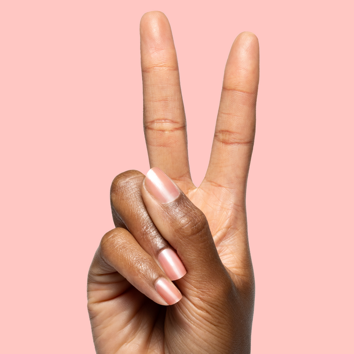Fingers showing glossy sheer warm peach pink nails painted with Pink Pineapple Gloss nail polish on soft pink background