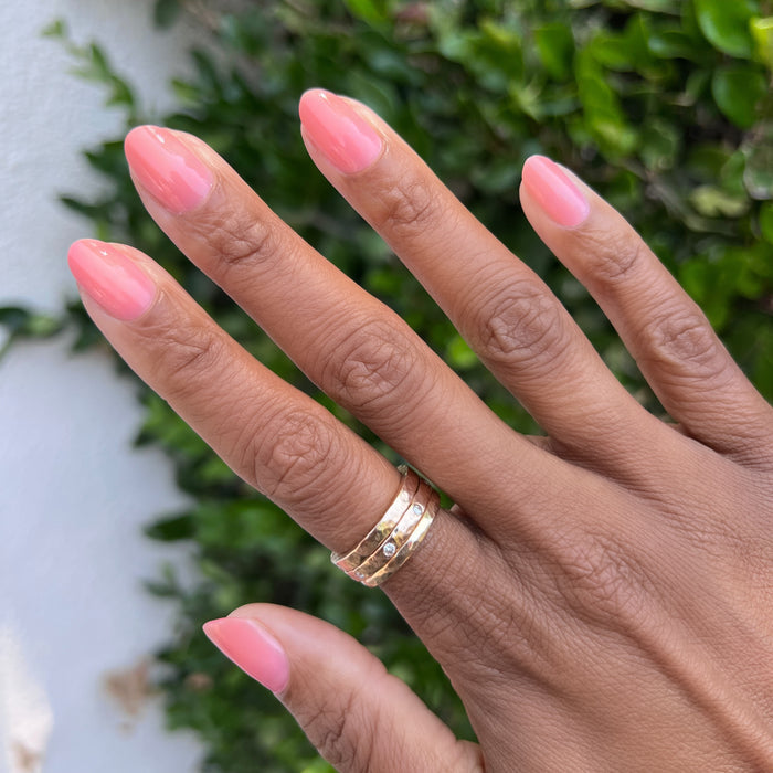 Fingers with medium almond nails painted in warm sheer peach pink using Pink Pineapple Gloss outdoors