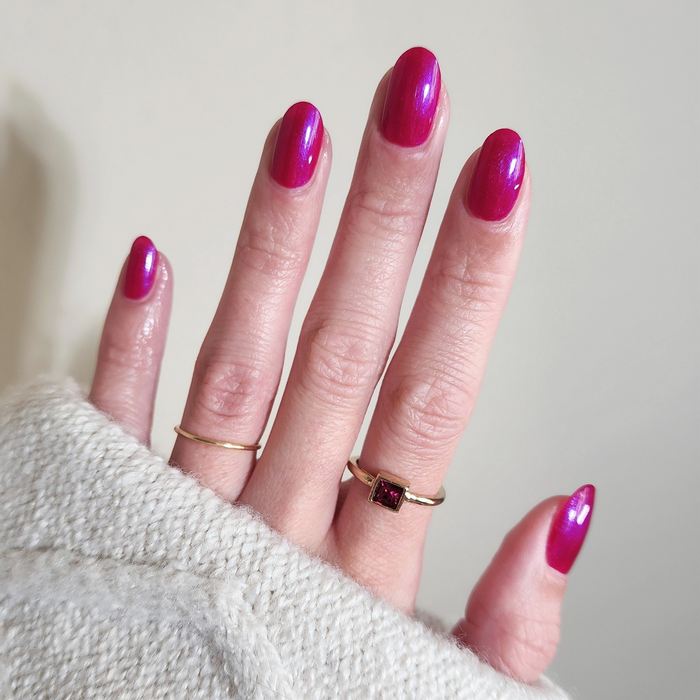 Pink Sapphire iridescent pink nail polish manicure on a light skin tone with a white sweater