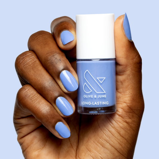 Hand with smooth nails painted in dusty ultramarine blue Rally Ready polish by Olive and June for a sporty mani look