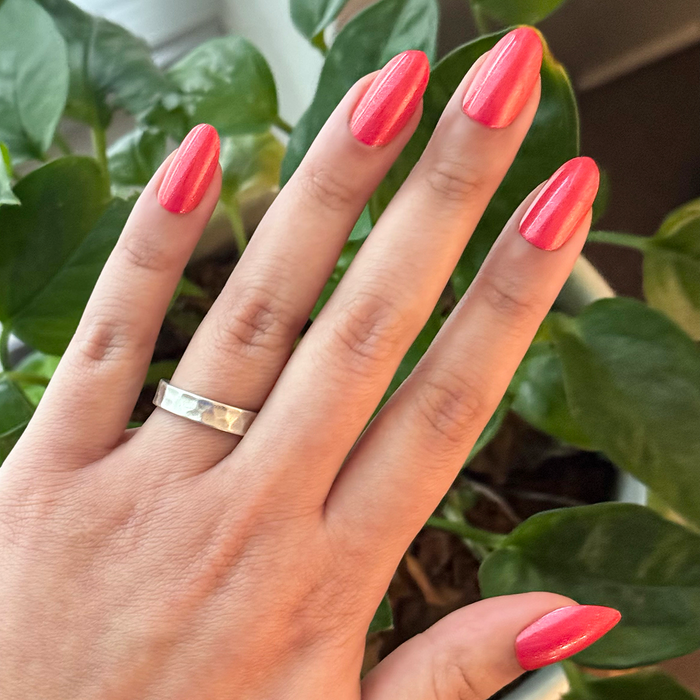 Hand wearing Rodeo Queen - Press-On | Medium | Oval bright pinky-red shimmer false nails in medium oval shape for at home mani