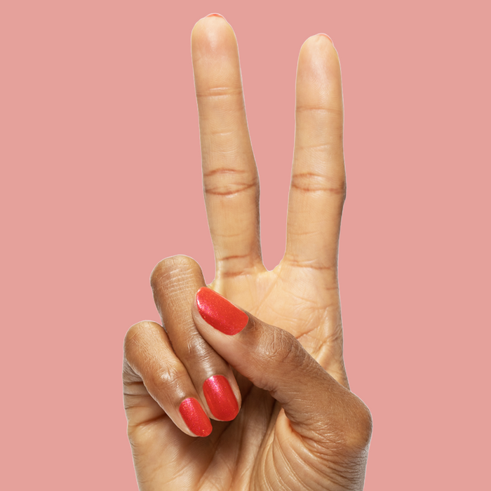 Hand showing peace sign with bright pinky-red silver shimmer nails painted with Rodeo Queen polish