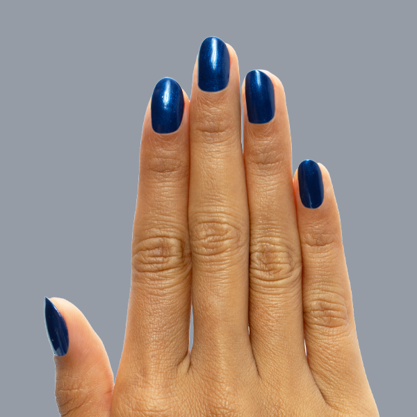 Hand with medium-length nails painted in Sapphire Season showing deep blue gel polish with shimmery chrome finish manicure