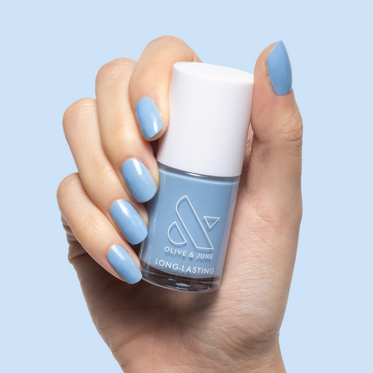 Hand with glossy nails painted in Shades of Seersucker holding Olive and June long-lasting gel polish bottle