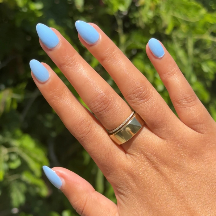 Hand with almond-shaped nails painted in smooth Shades of Seersucker gel polish for a bright summer manicure look