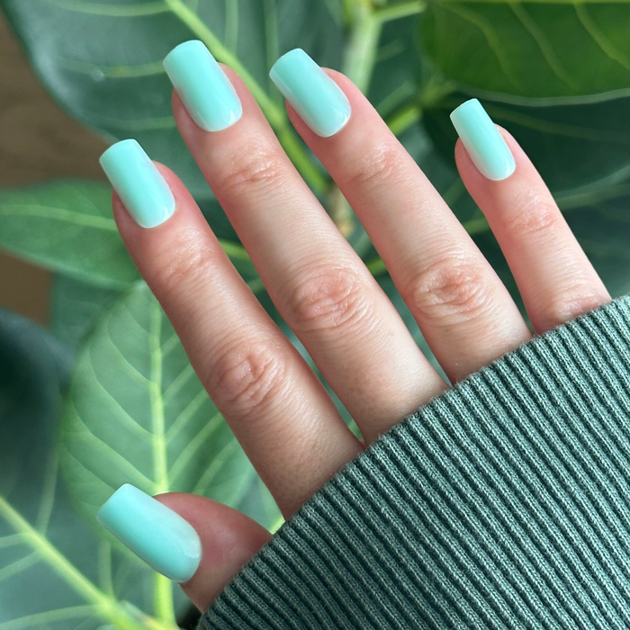 Slam Dunk - Press-On | Medium | Square turquoise false nails shown on hand with green leafy background for at-home mani