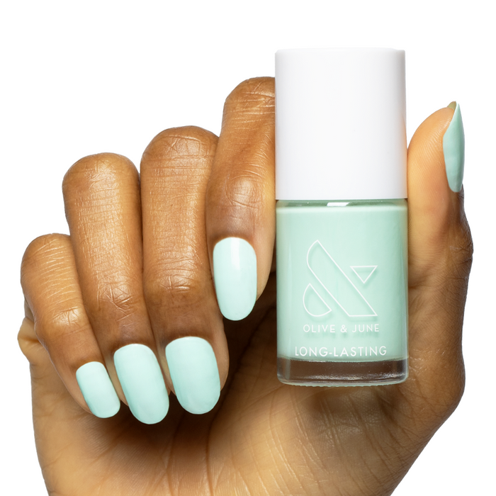 Hand with Slam Dunk turquoise nail polish holding matching Olive & June long-lasting gel polish bottle