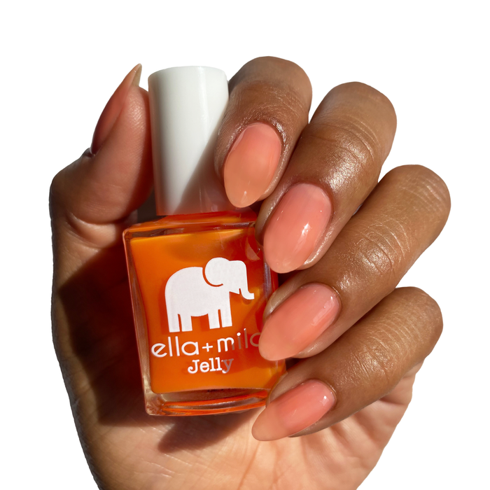 Spread the Love orange jelly nail polish on a deep skin tone, hand holding the bottle