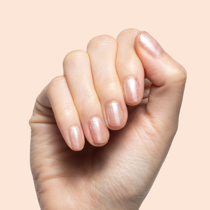 Hand with short natural nails painted in warm shimmering champagne using Starfruit Shimmer Gloss polish