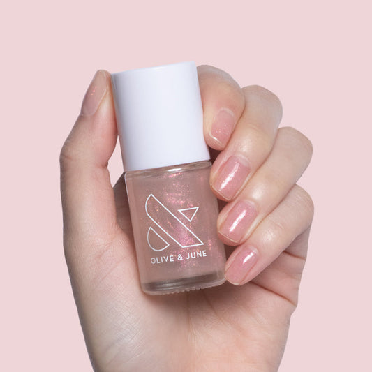 Hand holding Starshower rose gold glitter polish with nails shimmering for a delicate at home mani by Olive and June