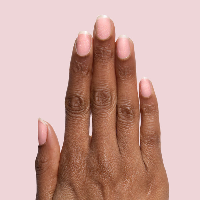 Hand with nails coated in delicate rose gold glitter using Starshower polish for a shimmering at home manicure