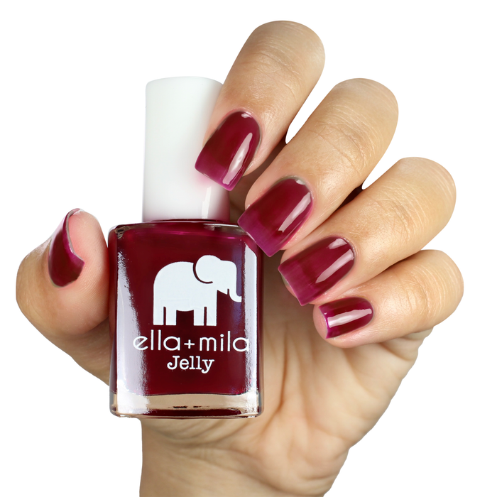 Suga Suga sheer fuchsia jelly nail polish on a medium skin tone, hand holding the bottle