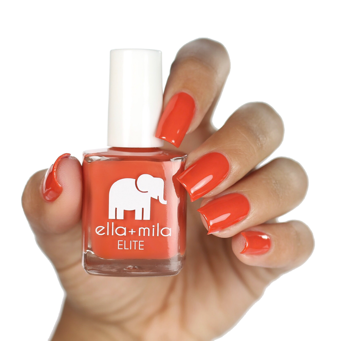 Sunset Escape burnt red-orange nail polish on a medium skin tone, hand holding the bottle