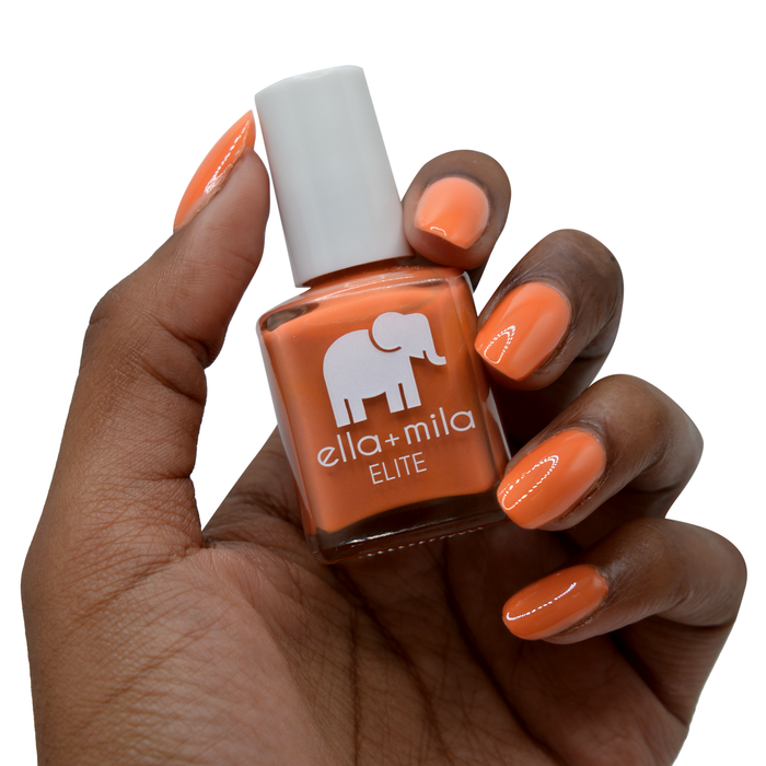 Sunset Escape burnt orange nail polish on a deep skin tone, hand holding the bottle