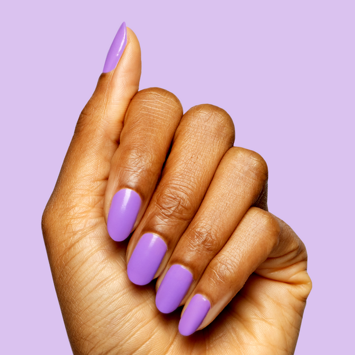 Hand with medium-length nails painted bright purple Tennis Skirt polish for a quick, bold at-home manicure look