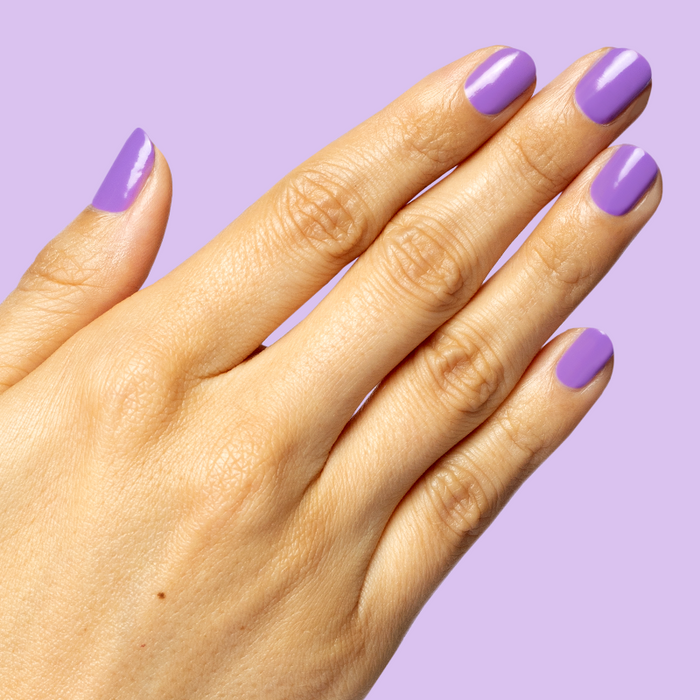 Hand with smooth nails painted bright purple Tennis Skirt polish for a fresh, glossy at-home manicure look