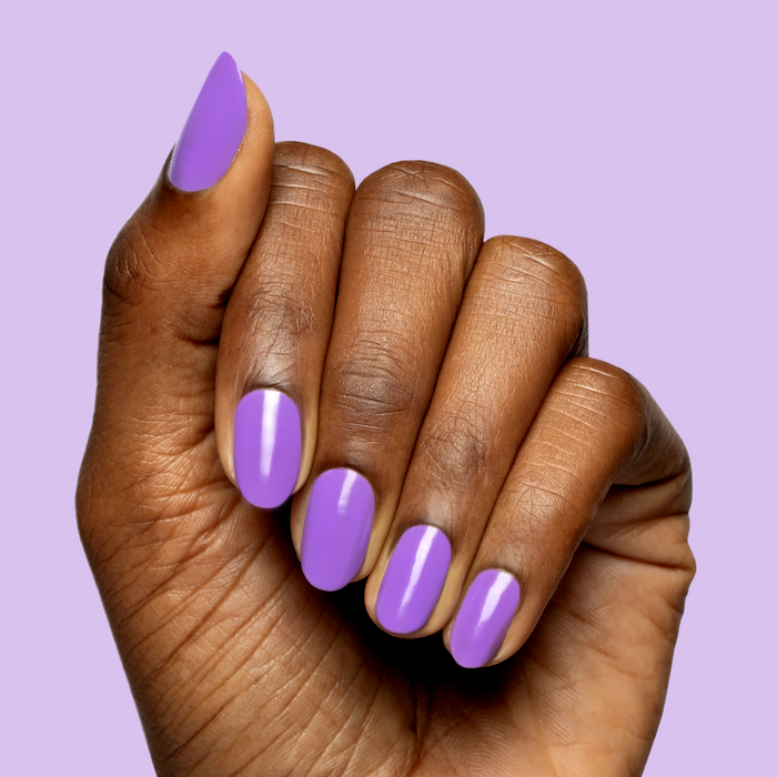 Hand with medium-length nails painted bright purple Tennis Skirt polish for a smooth, shiny at-home manicure by Olive and June
