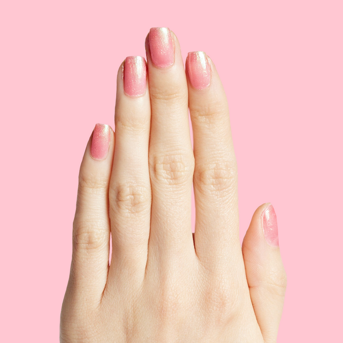 Hand with nails painted in shiny pink iridescent manicure using That’s Amoray polish on pink background