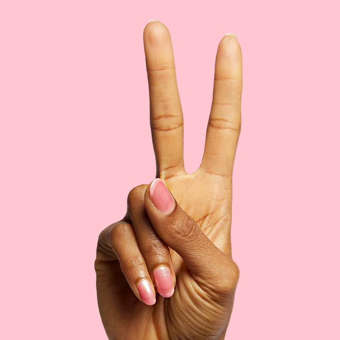 Hand showing two fingers with nails painted in shiny pink iridescent polish That’s Amoray on soft pink background