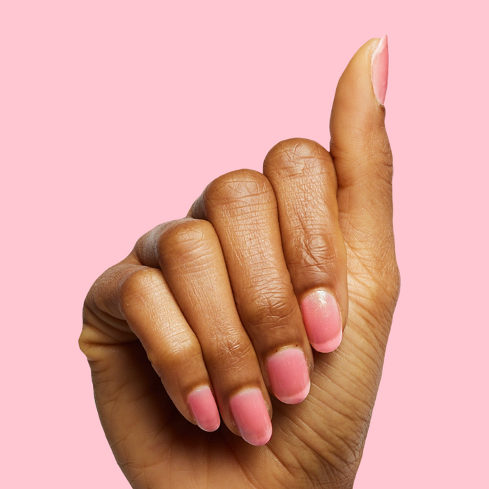 Hand with nails painted in sweet pink sheer manicure using That’s Amoray polish on pink background